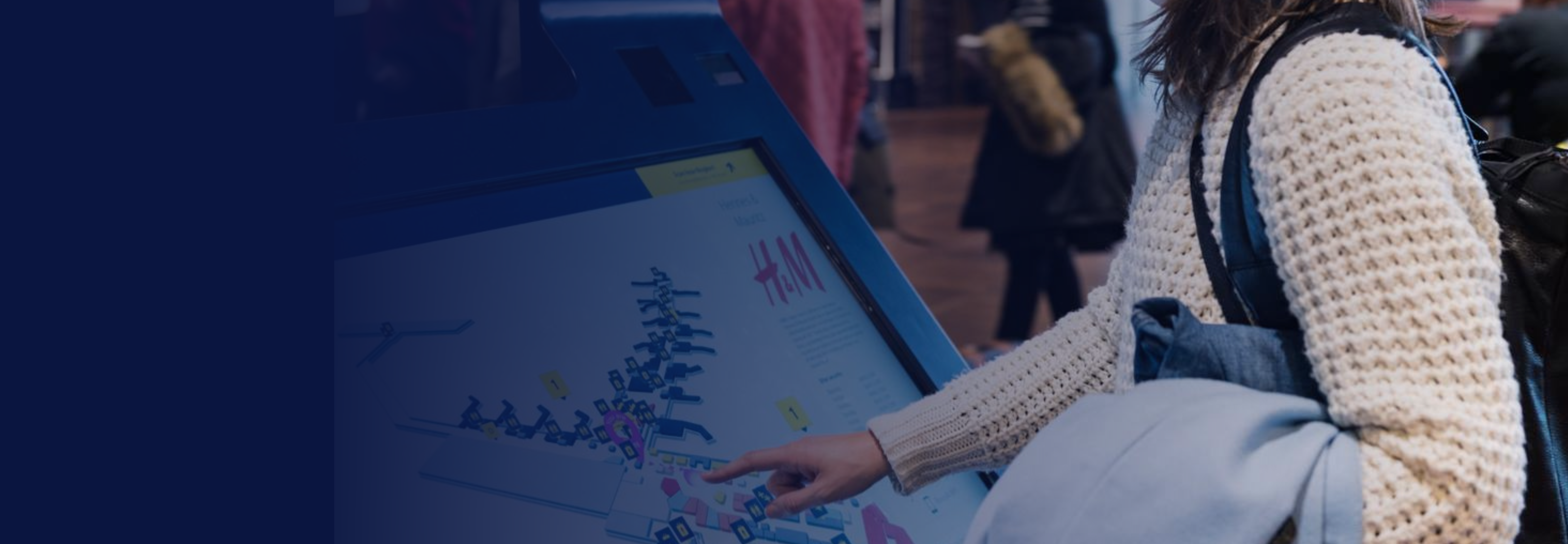 A passenger interacts with an interactive wayfinding kiosk at Copenhagen Airport, displaying real-time flight information and a 3D map to guide travelers through the terminal.