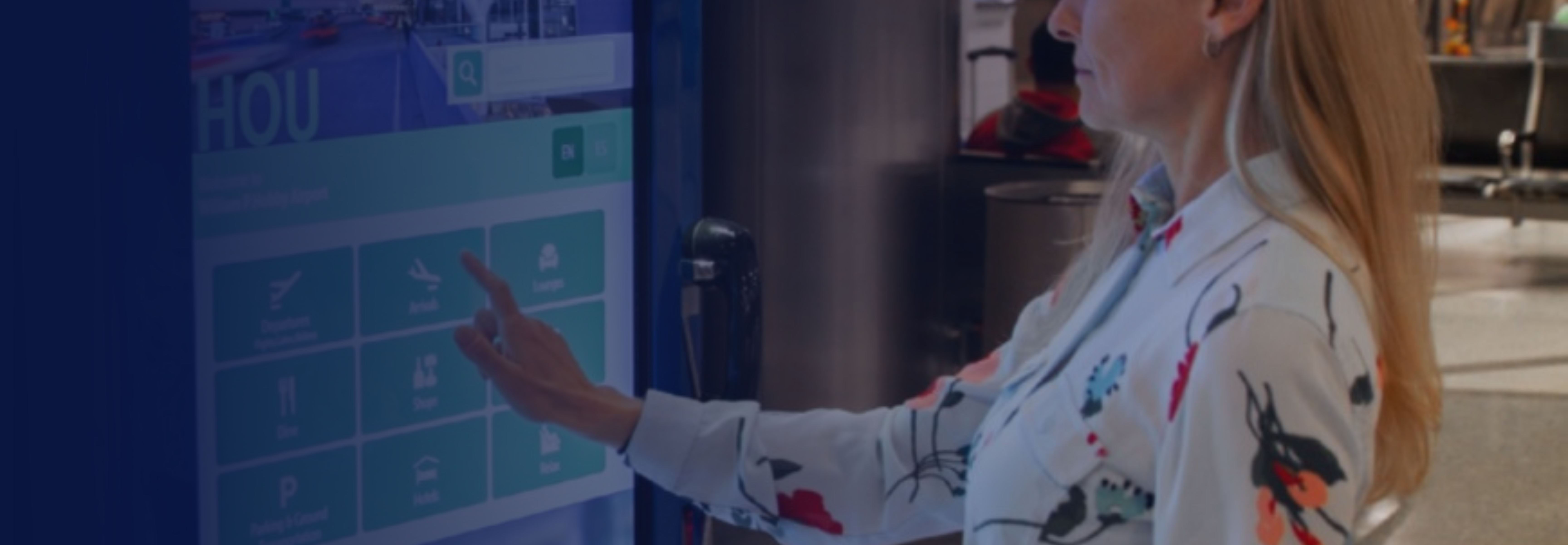 A woman uses an interactive wayfinding kiosk at George Bush Intercontinental Airport (IAH) to access flight information and navigation directions.