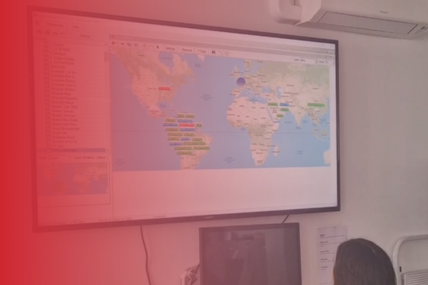 Technicien ViaDirect supervisant à distance une borne interactive dans un centre commercial, sur fond de carte du monde affichant plusieurs points de présence internationale.