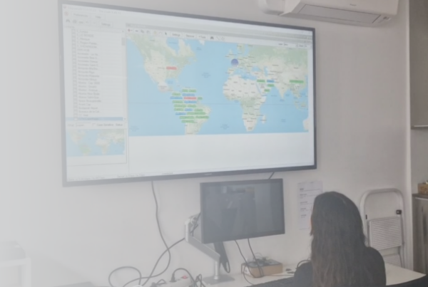 Technicien ViaDirect supervisant à distance une borne interactive dans un centre commercial, sur fond de carte du monde affichant plusieurs points de présence internationale.