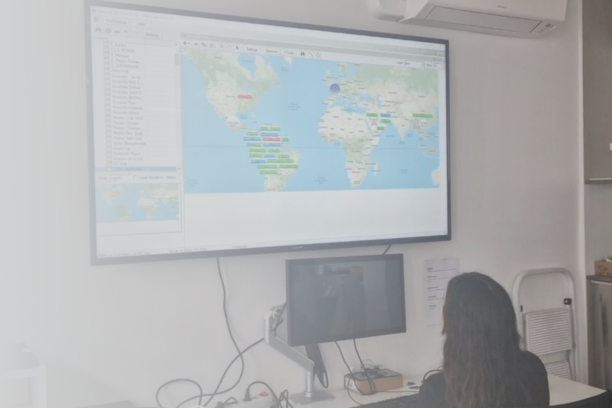 Technicien ViaDirect supervisant à distance une borne interactive dans un centre commercial, sur fond de carte du monde affichant plusieurs points de présence internationale.
