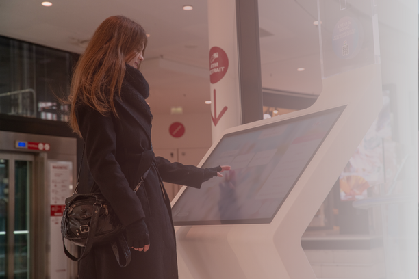 Woman using a ViaDirect interactive wayfinding kiosk in a shopping center