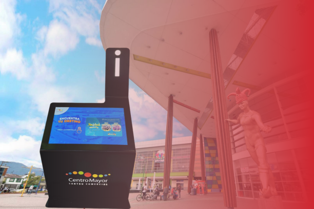 Tótem de orientación digital de ViaDirect frente a la entrada principal del Centro Comercial Centro Mayor en Bogotá, con interfaz interactiva visible y escultura icónica al fondo.