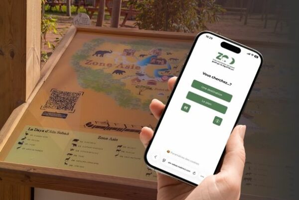 Smartphone displaying ViaDirect’s interactive mobile map at Ain Sebaa Zoo, next to physical zoo signage with a QR code for instant digital wayfinding access.