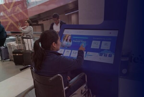 Passenger using an accessible interactive wayfinding kiosk at an airport while seated in a wheelchair.