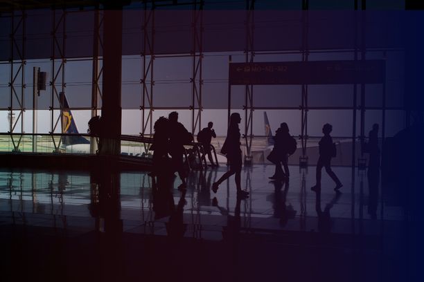Passengers walking through a large airport terminal, illustrating the challenges of navigation and wayfinding in complex transportation hubs.