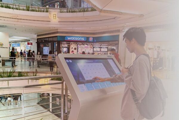 Visitor using a ViaDirect interactive wayfinding kiosk inside a shopping mall to navigate stores and services.