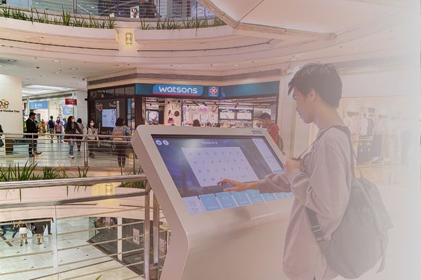 Visitor using a ViaDirect interactive wayfinding kiosk inside a shopping mall to navigate stores and services.